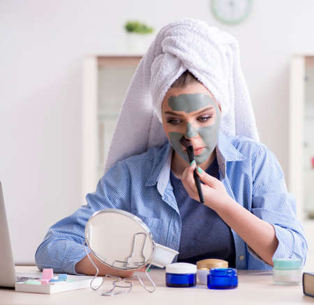 Woman applying clay mask with brush at homeの写真素材