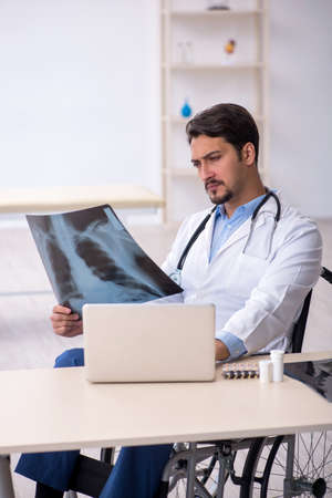 Young male doctor in wheel-chair working in the clinicの写真素材