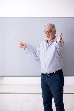 Old male teacher in front of whiteboardの写真素材