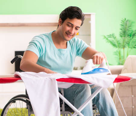 Disabled man on wheelchair ironing clothingの写真素材