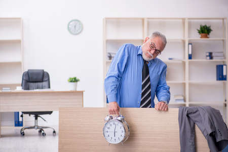 Old male employee in time management conceptの写真素材