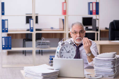 Old male employee in time management conceptの写真素材