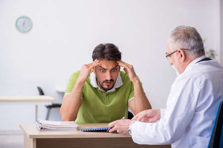 Young man visiting old male doctorの写真素材