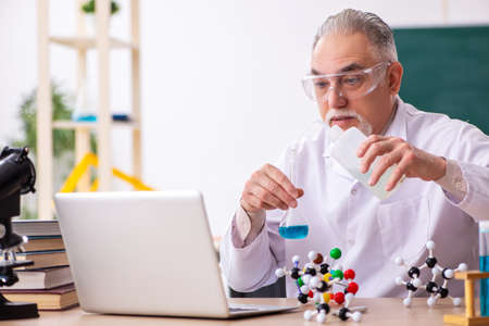 Old male teacher chemist in the classroom