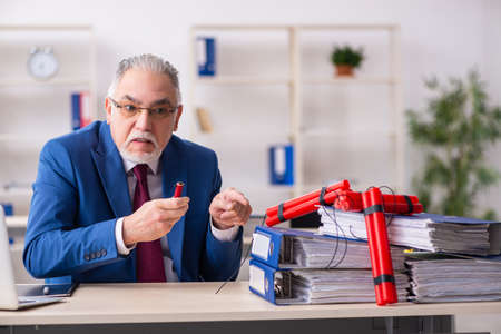 Old male employee with dynamite in the officeの写真素材