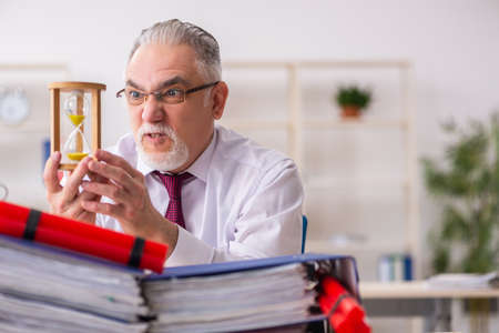 Old male employee with dynamite in the office