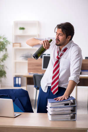 Young alcohol addicted male employee working in the officeの写真素材