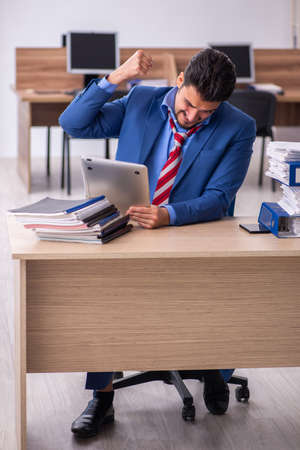 Young male employee unhappy with excessive work at workplaceの写真素材