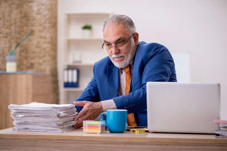 Old businessman employee sitting in the officeの写真素材