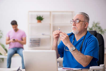 Old male doctor and young male patient in vaccination concept