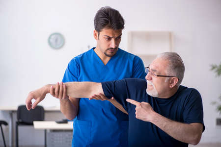 Old man visiting young male doctorの写真素材