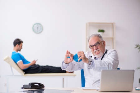 Young male patient visiting old male doctor gastroenterologistの写真素材