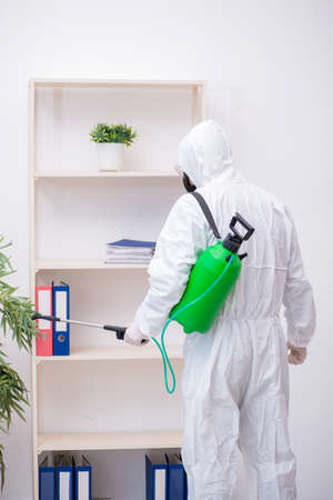 Young male contractor disinfecting office during pandemicの写真素材