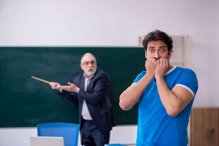 Old male teacher and young male student in front of blackboardの写真素材