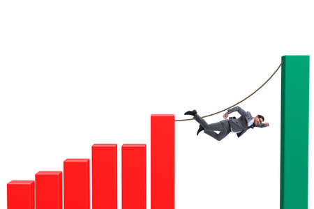 Businessman walking on tight rope between bar chartの写真素材