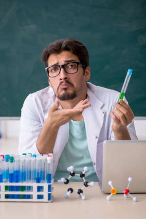 Young male chemist in front of blackboard