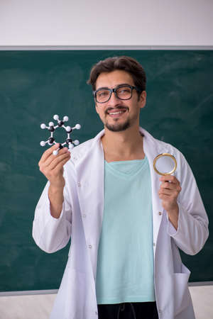 Young male chemist in front of blackboardの写真素材