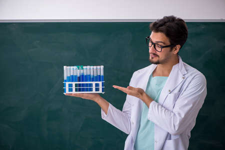 Young male chemist in front of blackboard