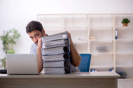 Young male employee and too much work in the office