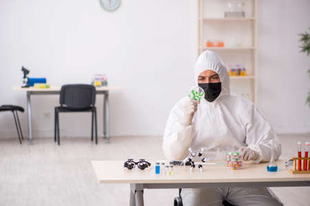 Young male chemist in drugs synthesis concept
