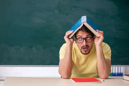 Young male student in front of blackboard