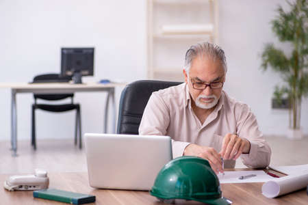 Old male architect working in the office