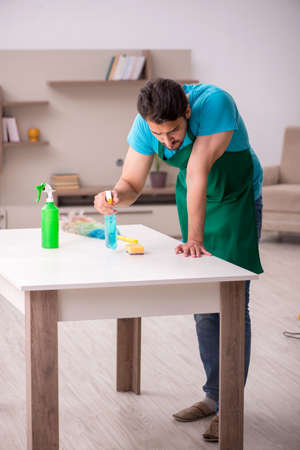 Young male contractor cleaning the houseの写真素材