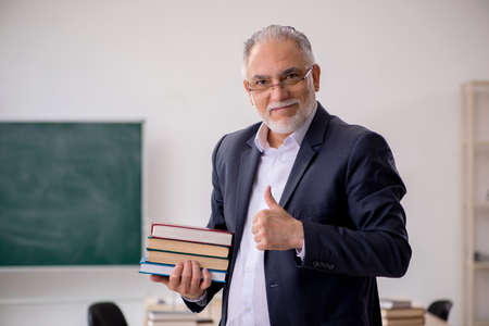 Old male teacher in front of blackboardの写真素材