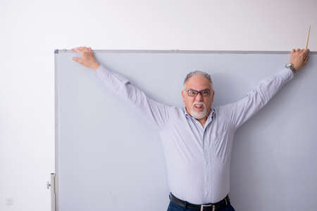 Old male teacher in front of whiteboardの写真素材