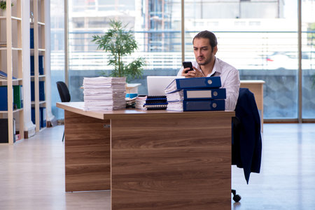 Young male employee unhappy with excessive work in the officeの写真素材