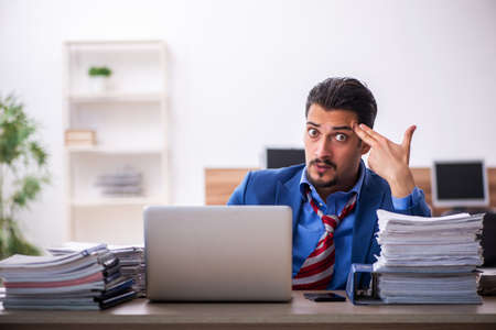 Young male employee unhappy with excessive work at workplaceの写真素材