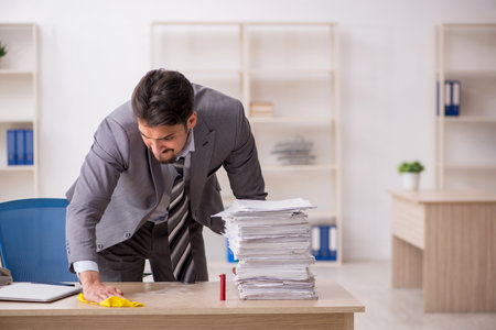 Young male employee unhappy with excessive work in the officeの写真素材