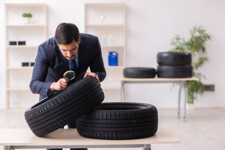 Young man inspecting tires in the officeの写真素材