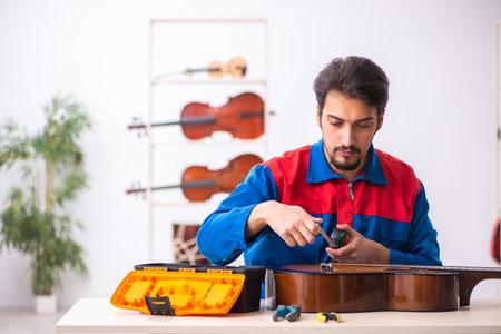 Young male repairman repairing musical instruments at workplaceの素材 [FY310174598103]