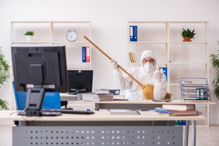 Old male contractor cleaning the office holding broomの写真素材