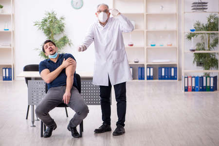 Young male patient visiting old male doctor in vaccination conceの写真素材