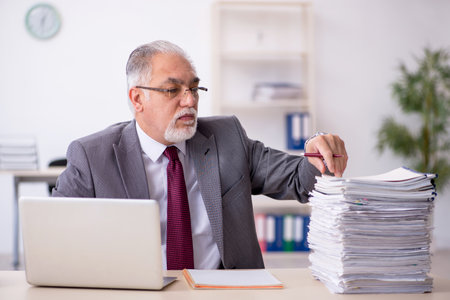 Old male employee and too much work in the officeの写真素材
