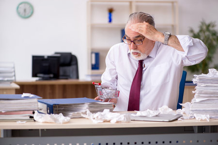 Old male employee unhappy with excessive work in the officeの写真素材