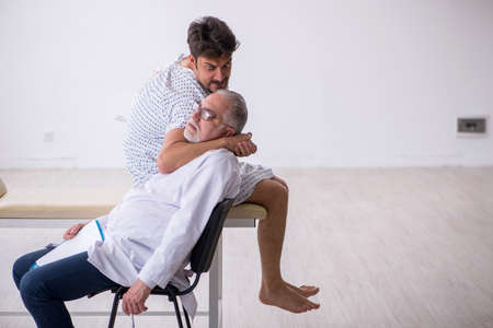 Old male doctor psychiatrist examining young male patientの写真素材