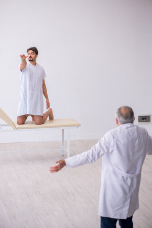Old male doctor psychiatrist examining young male patientの写真素材