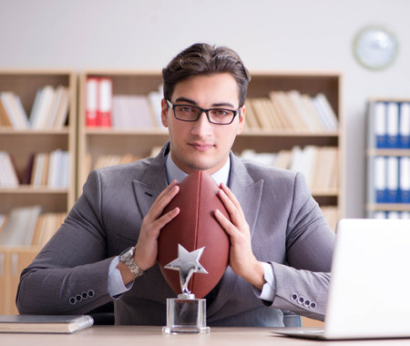 Businessman with american football in officeの写真素材