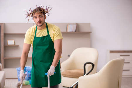 Young male contractor wearing prickly wreath on head cleaning thの写真素材