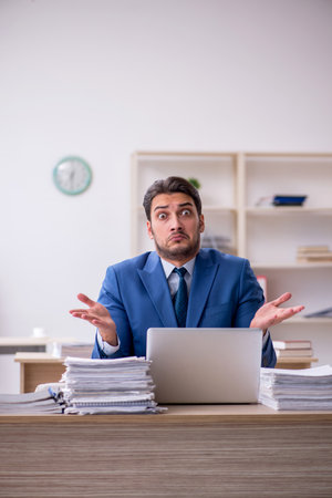 Young businessman employee and too much work in the officeの写真素材