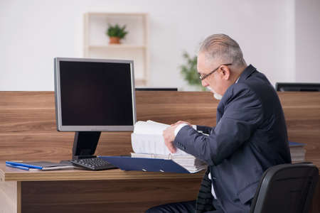 Aged male employee sitting at workplaceの写真素材