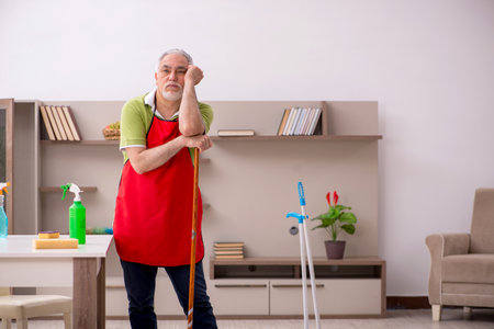 Old man cleaning the houseの写真素材