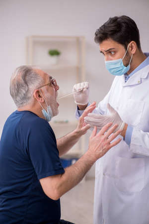 Old patient visiting young male doctor otorhinolaryngologistの写真素材