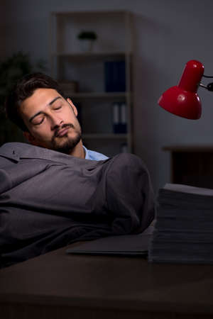 Young male employee working late in the officeの写真素材