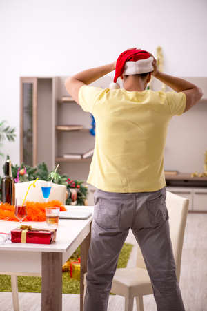 Young man cleaning the apartment after Christmas partyの写真素材