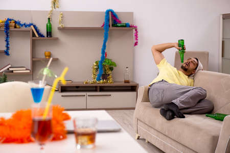Young man cleaning the apartment after Christmas partyの写真素材