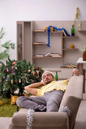 Young man cleaning the apartment after Christmas partyの写真素材